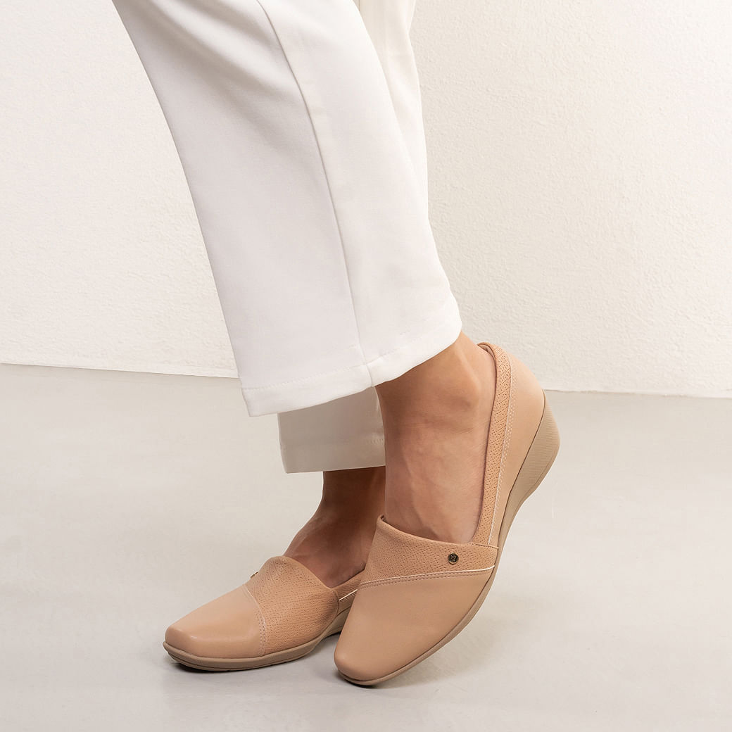 Close lateral do sapato mocassim nude Piccadilly mostrando acabamento perfurado e salto cunha