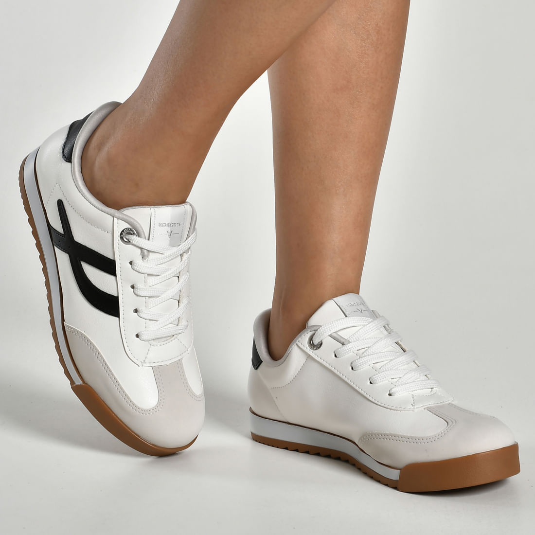 Tênis casual feminino branco com detalhes pretos e sola marrom visto de lado