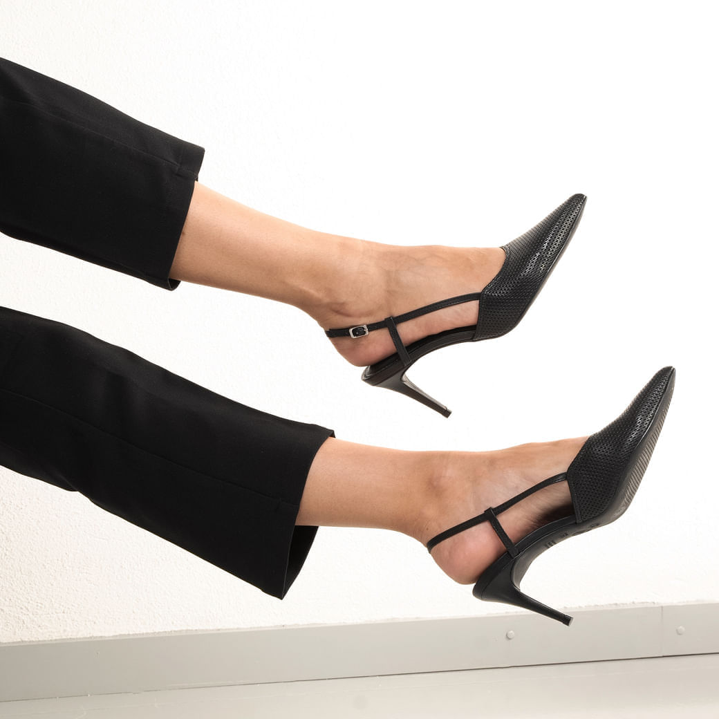 Close lateral do scarpin preto slingback com tiras finas e salto fino, destacando o bico fino