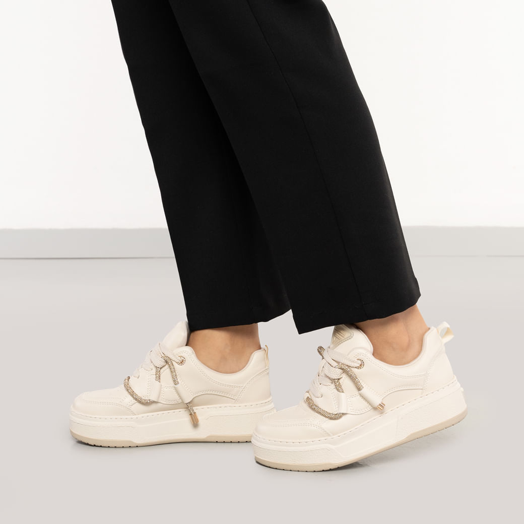 Tênis casual feminino Via Marte em ângulo lateral mostrando sola elevada e detalhes dourados