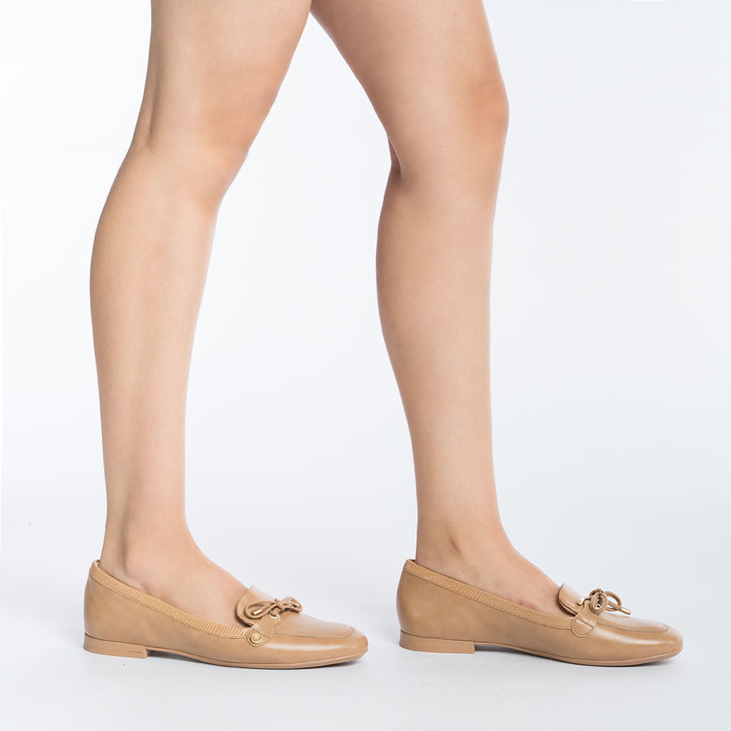 Vista lateral do sapato mocassim feminino em couro caramelo com detalhes dourados
