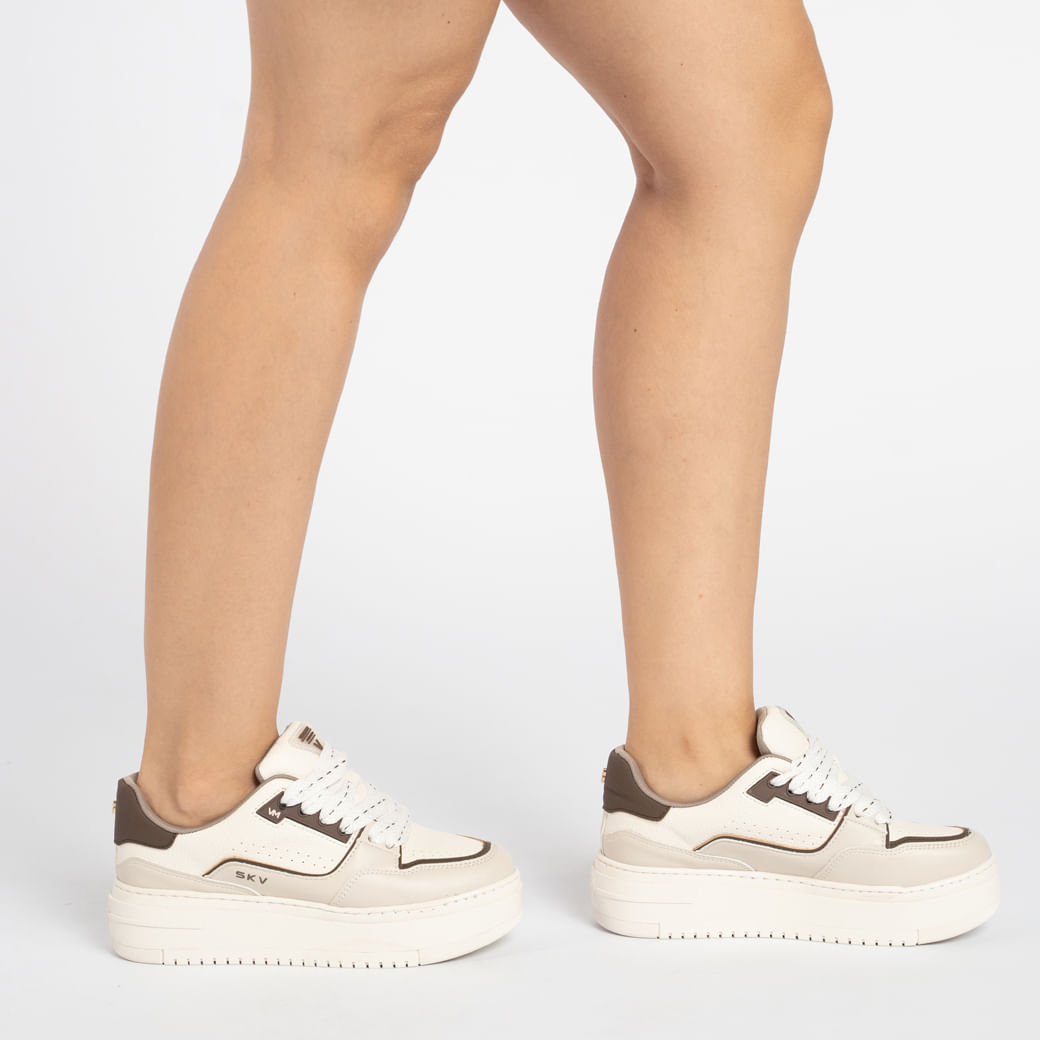 Tênis Flatform Via Marte Branco Feminino visto de lado, evidenciando perfuros laterais e cadarços em destaque.