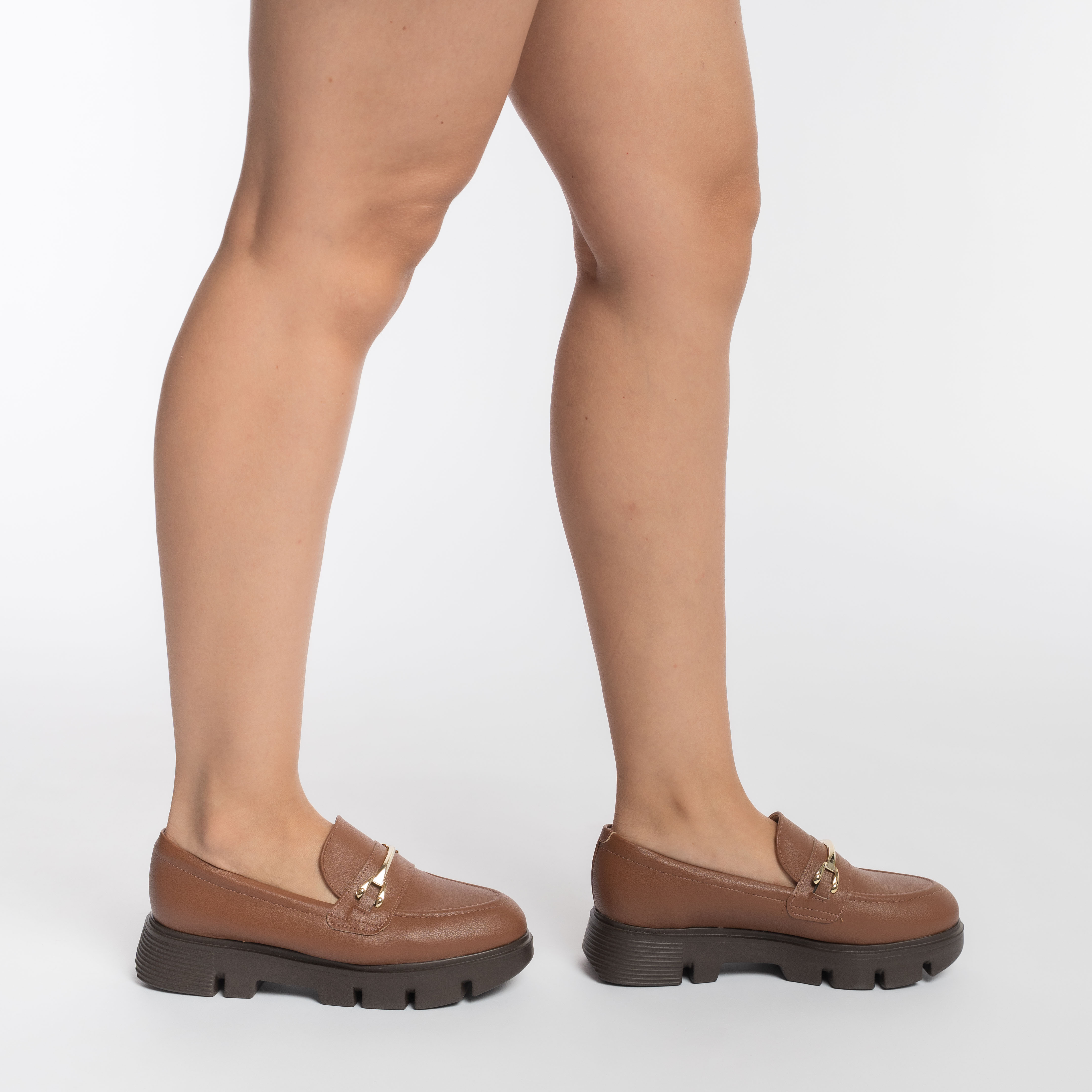 Vista lateral do sapato mocassim feminino marrom avelã com fivela decorativa dourada