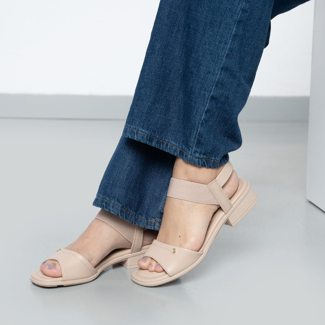 Sandália Comfortflex vista lateral esquerda mostrando salto bloco de 3 cm e design em material sintético creme com detalhes dourados.