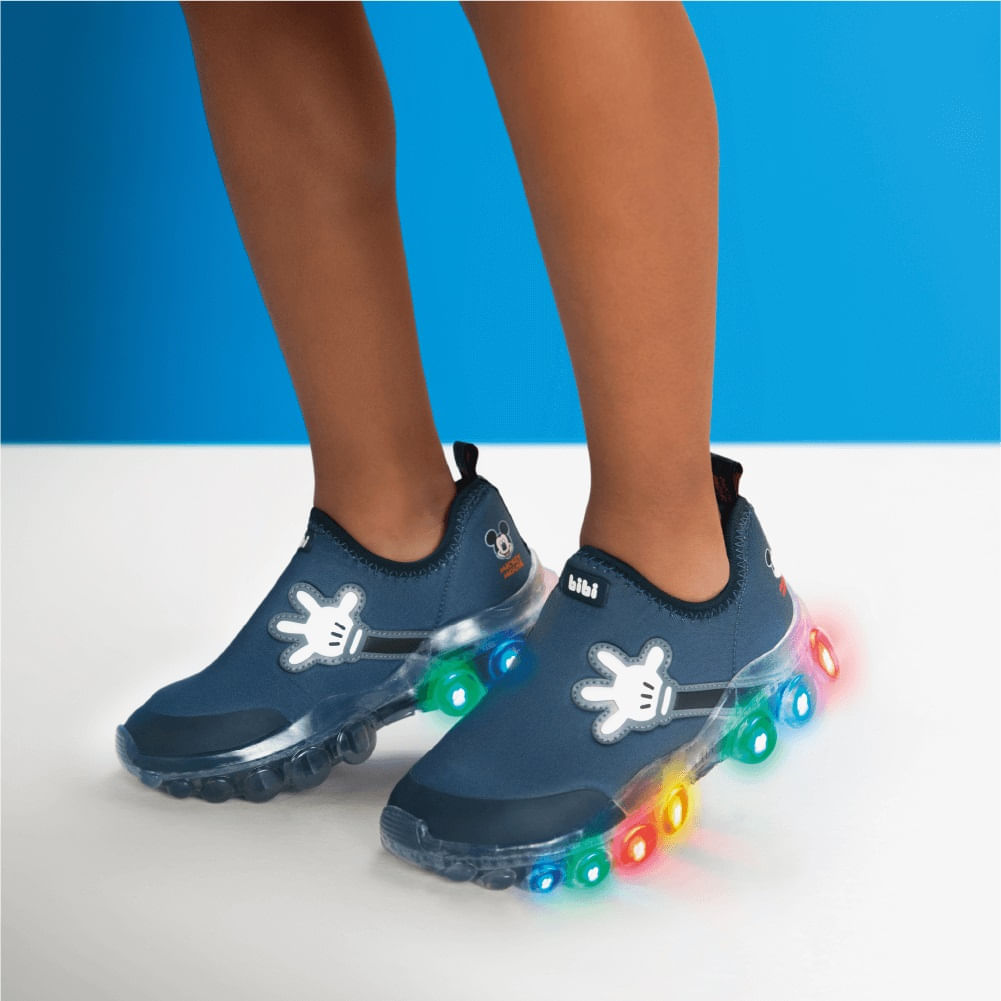 Tênis infantil marinho com luzes LED, usado por criança, destacando o conforto e estilo