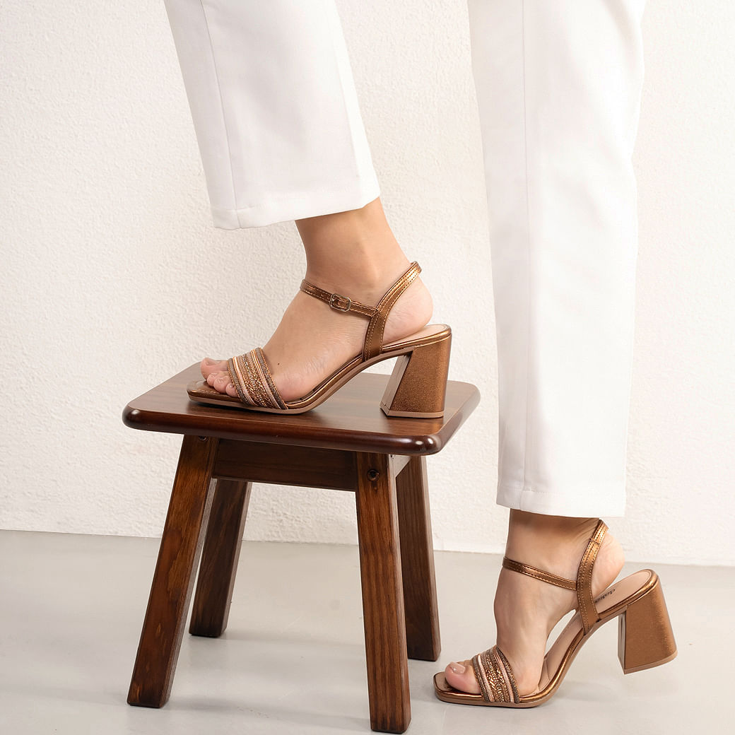 Vista lateral da sandália feminina Dakota bronze evidenciando a tira frontal trabalhada e salto bloco médio.