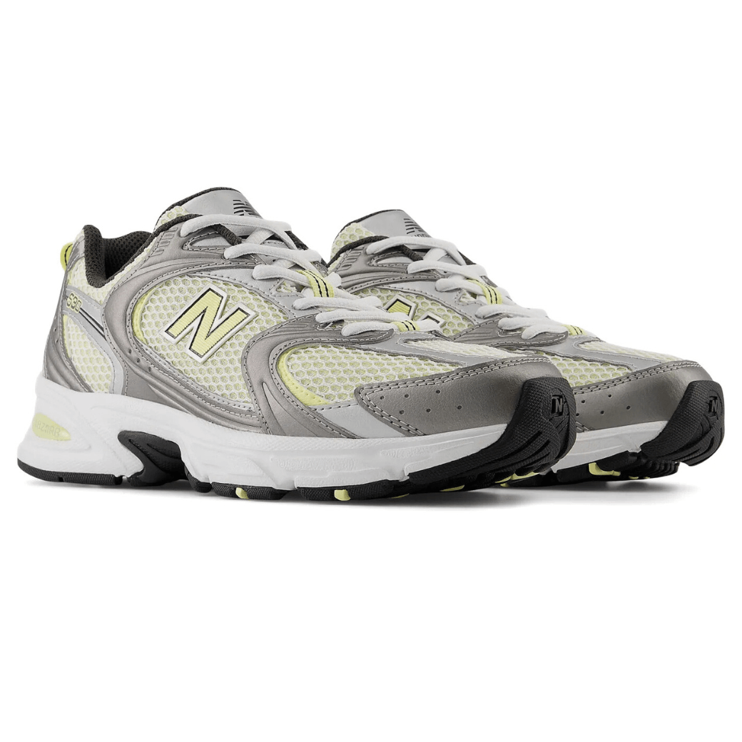 Par de tênis New Balance 530 feminino cinza mostrando laterais internas e biqueiras com detalhes em camurça e malha respirável
