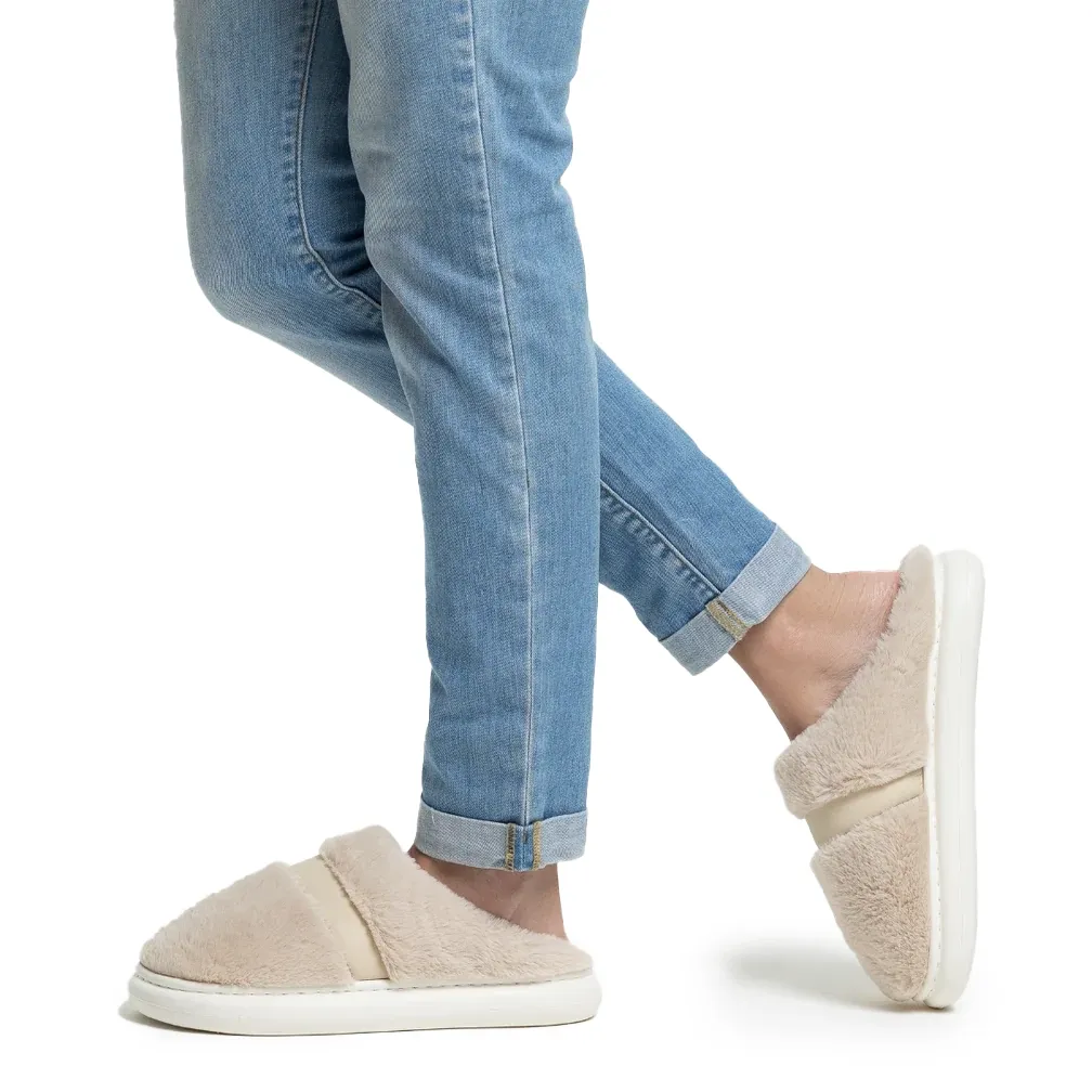 Vista lateral da pantufa Flowfa Celine bege com modelo usando jeans, destacando conforto e estilo casual.