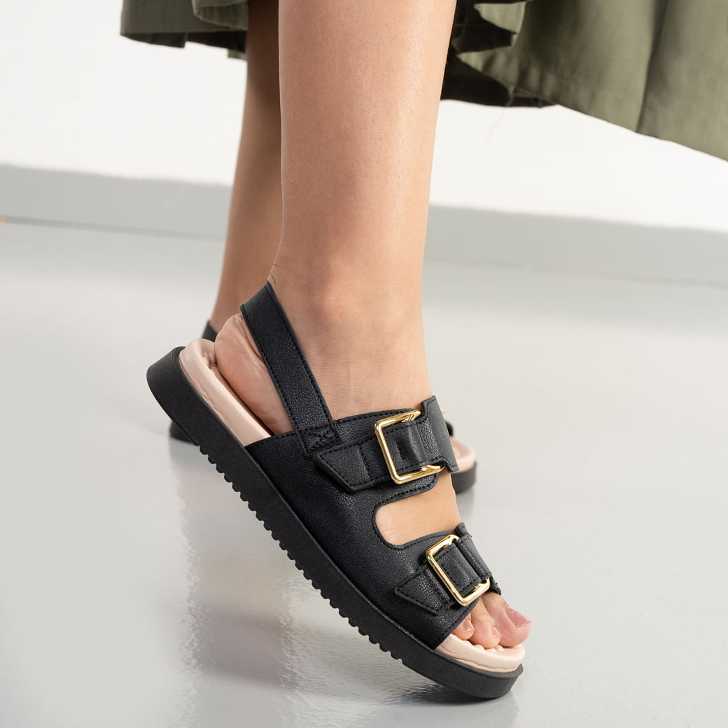 Sandália feminina casual preta e bege Modare com fivelas douradas, usada em pé com saia verde.