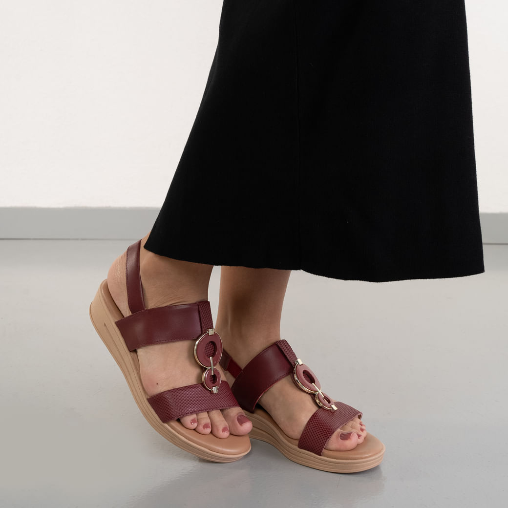 Sandália feminina Usaflex REBU MM070508 couro vinho com detalhe metálico dourado, usada por modelo.