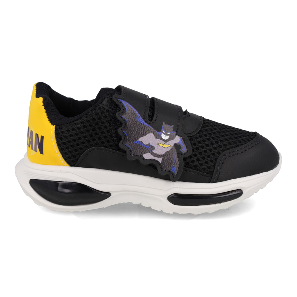 Tênis infantil preto com detalhes amarelos e aplique do Batman em relevo na lateral, fechamento em velcro duplo e solado branco com detalhes pretos